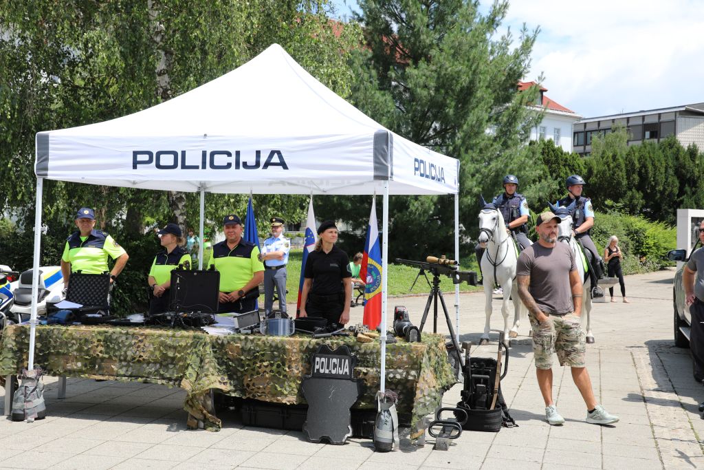 Stojnica z napisom POLICIJA s sodelujočimi policisti in mimoidočimi na Slovenskem trgu v Kranju