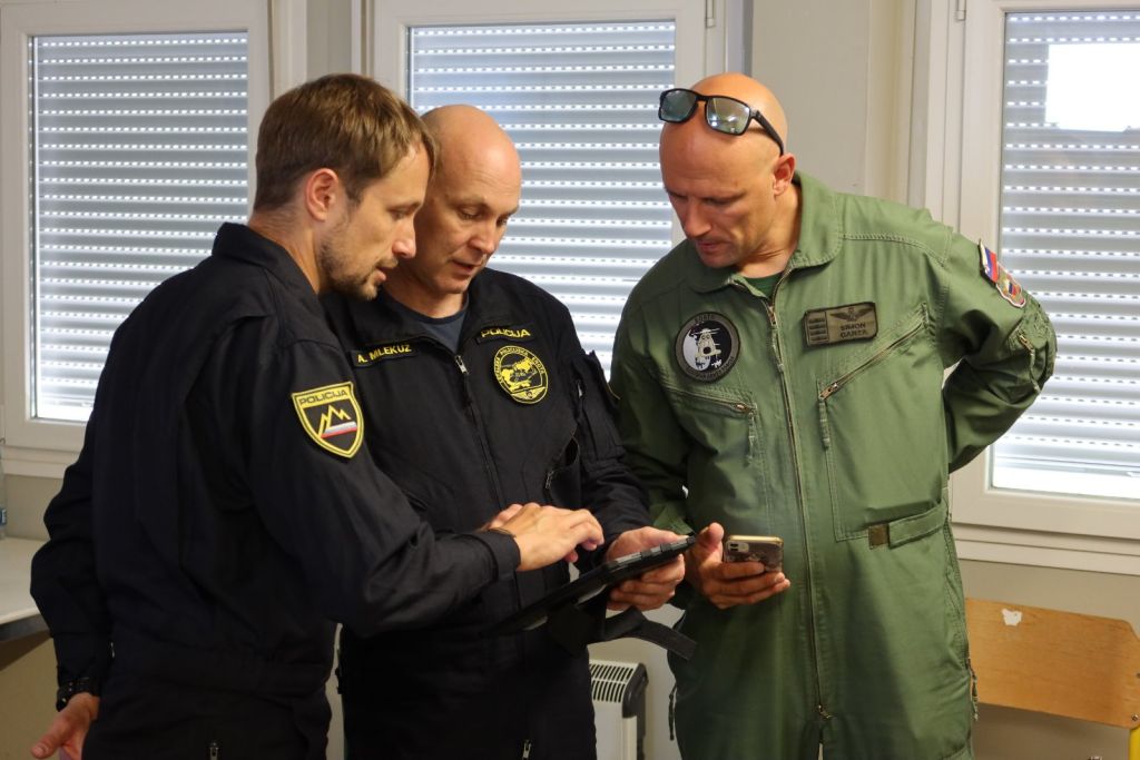 Člana posadke policijskega helikopterja v pogovoru s kolegom iz Slovenske vojske