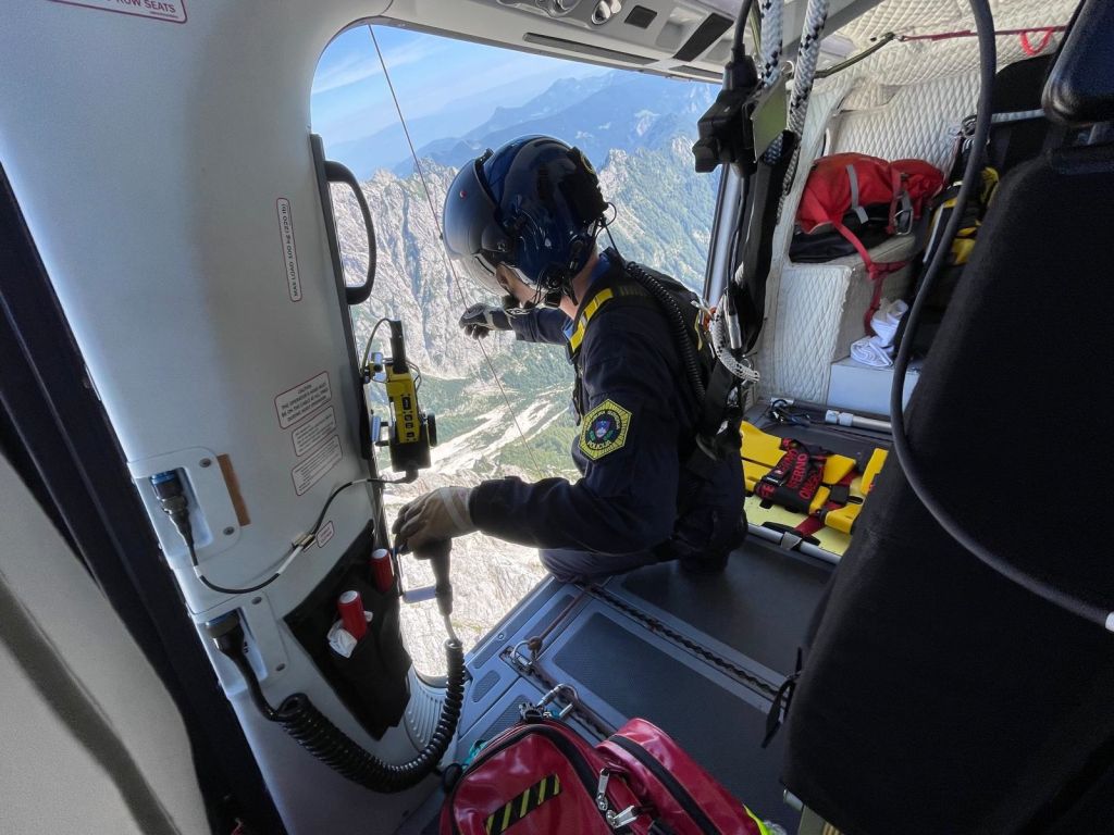 Reševalec v helikopterski kabini, spušča jeklenico iz helikopterja
