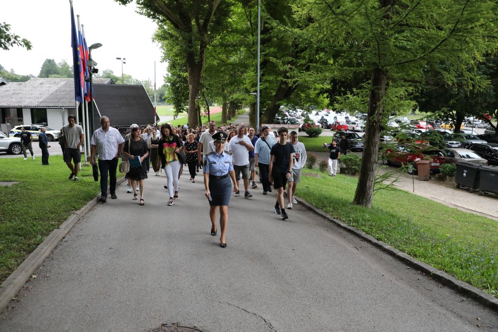 Na fotografiji obiskovalci dogodka pod vodstvom policistke vstopajo v območje Policijske akademije.