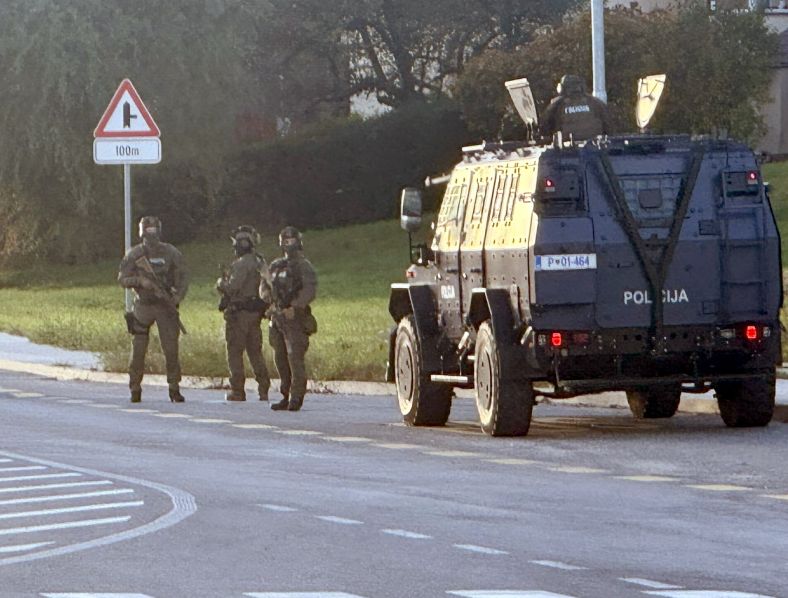 Policijsko vozilo in trije pripadniki Specialne enote stojijo na cesti