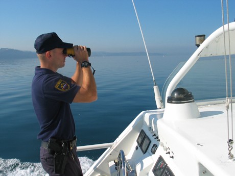 picture of a police officer on a police boat with binoculars