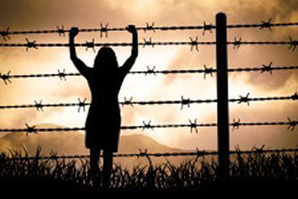 slika silhuete ženske pred žično ograjo z dvignjenimi rokami