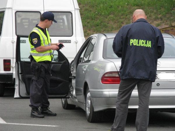 slika dveh policistov, ki pregledujeta ustavljeno vozilo